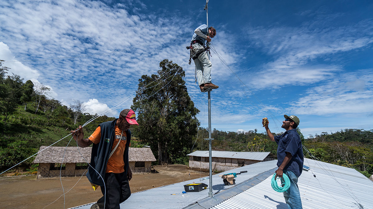 Joey Redhead (C) & David Feka (R) install an antenna on the roof of a remote primary school in PNG