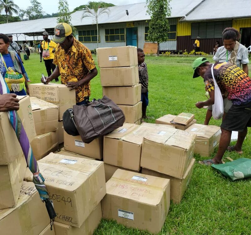 People picking up cardboard boxes with books inside.