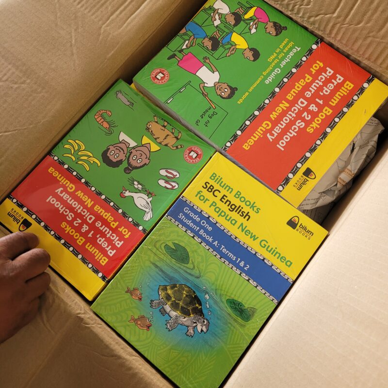 Colourful children's books in a cardboard box.