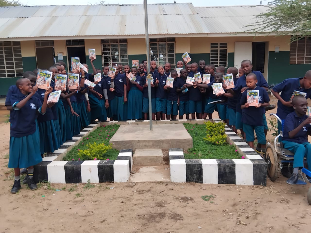 Students hold up their new Bibles paid for by MAF supporters (credit: HFTM)